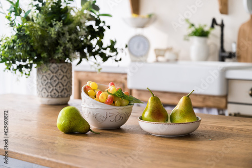 ripe pears and grape on plate on wooden dining table at kitchen