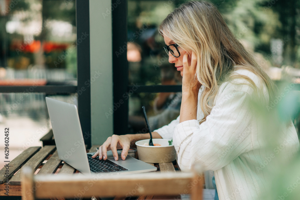 Business woman working remotely while sitting in a cafe in summer. Business woman working remotely while sitting in a cafe in summer.