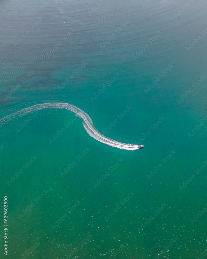 Aerial view of a boat sailing along Baia de Sao Martinho do Porto, a small bay with beach in Portugal. Aerial view of a boat sailing along Baia de Sao Martinho do Porto, a small bay with beach in Portugal.