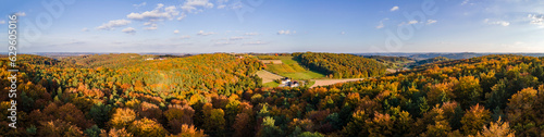 Aerial drone panoramic view of the autumn colours as the sun sets in the hill country on the border of Burgenland and Styria under scattered clouds, Bad Loipersdorf, Styria, Austria.