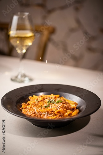 Bowl of delicious penne pasta with cheese and sauce on the table