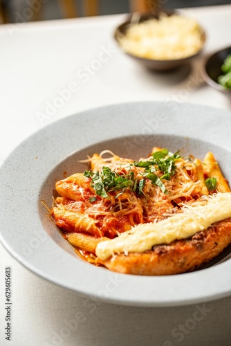 Bowl of delicious penne pasta with cheese and sauce on the table