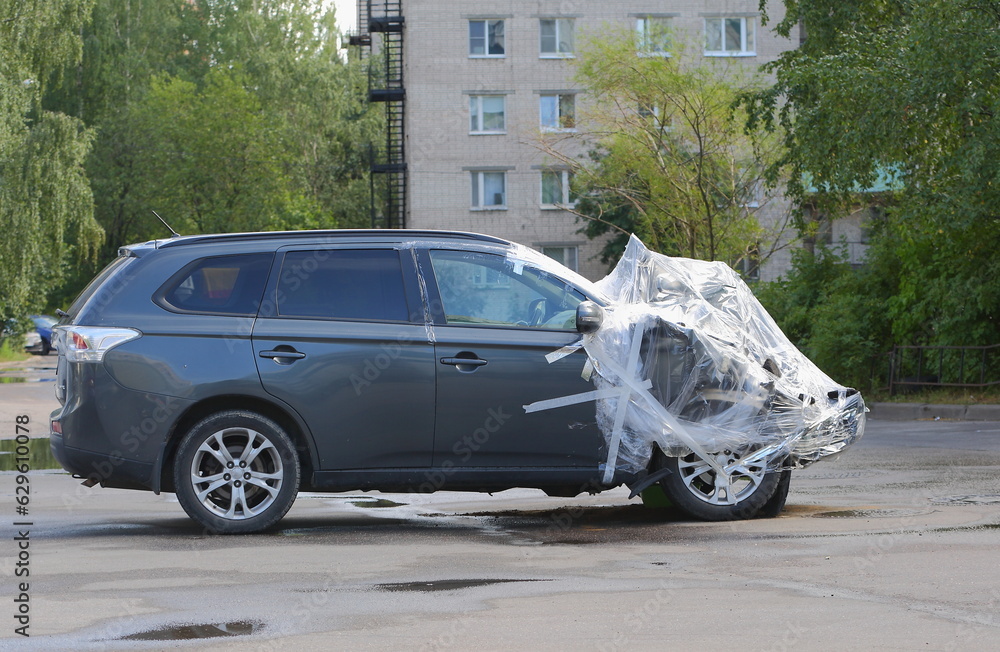 A new black wrecked car after an accident is covered with plastic wrap, Iskrovsky Prospekt, Saint Petersburg, Russia, July 24, 2023