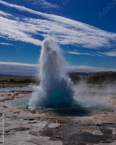 Majestic geyser erupting on the side of Iceland against a blue sky