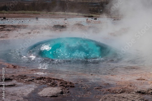 Majestic geyser erupting on the side of Iceland against a blue sky