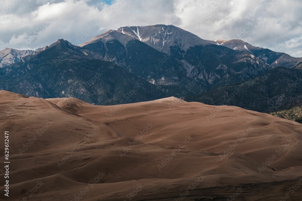 Naklejka premium Great Sand Dunes National Park, featuring sandy dunes with a mountain and sky backdrop