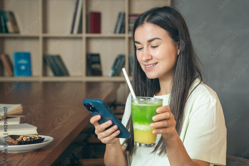 Woman in a cafe with a smartphone and a glass of lemonade. Woman in a cafe with a smartphone and a glass of lemonade.