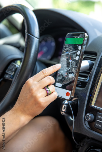 Female driver hand holding a phone with interface navigator on a screen. © puhimec
