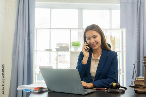 Asian female lawyer in formal dress Work with laptops and law books, hammers and scales, real estate work and dispute contract documents for defense strategies. Fight for freedom 