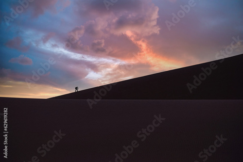 Namibia, the Namib desert, a man climbing on the dune, sunrise in backlight
 photo