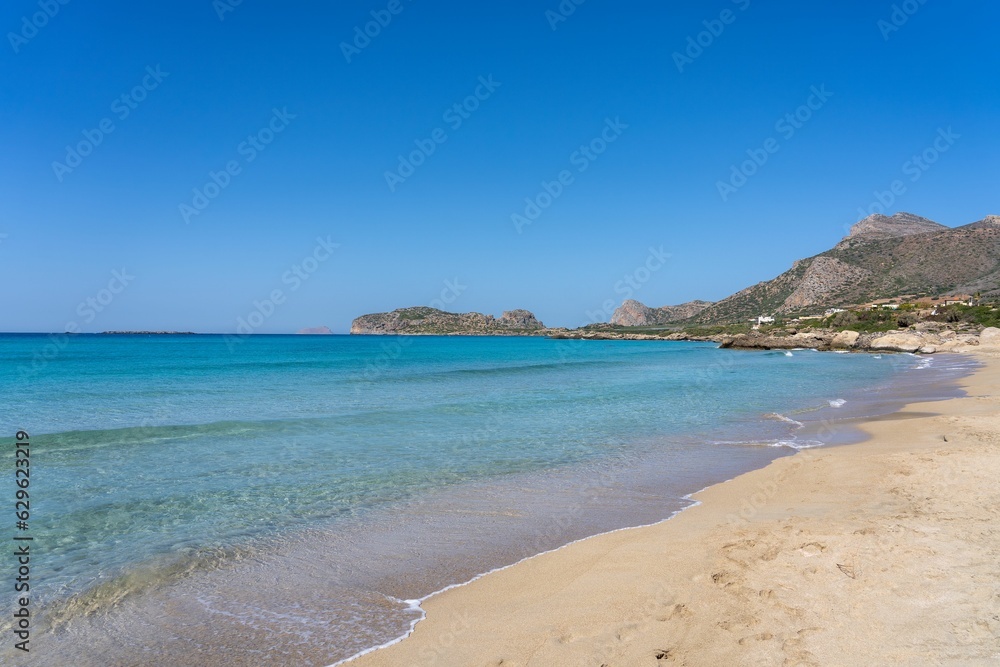 Tranquil scene of blue waters lapping against a beach with mountains in the background in Greece