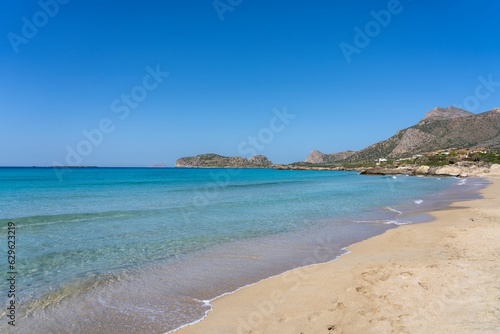 Tranquil scene of blue waters lapping against a beach with mountains in the background in Greece