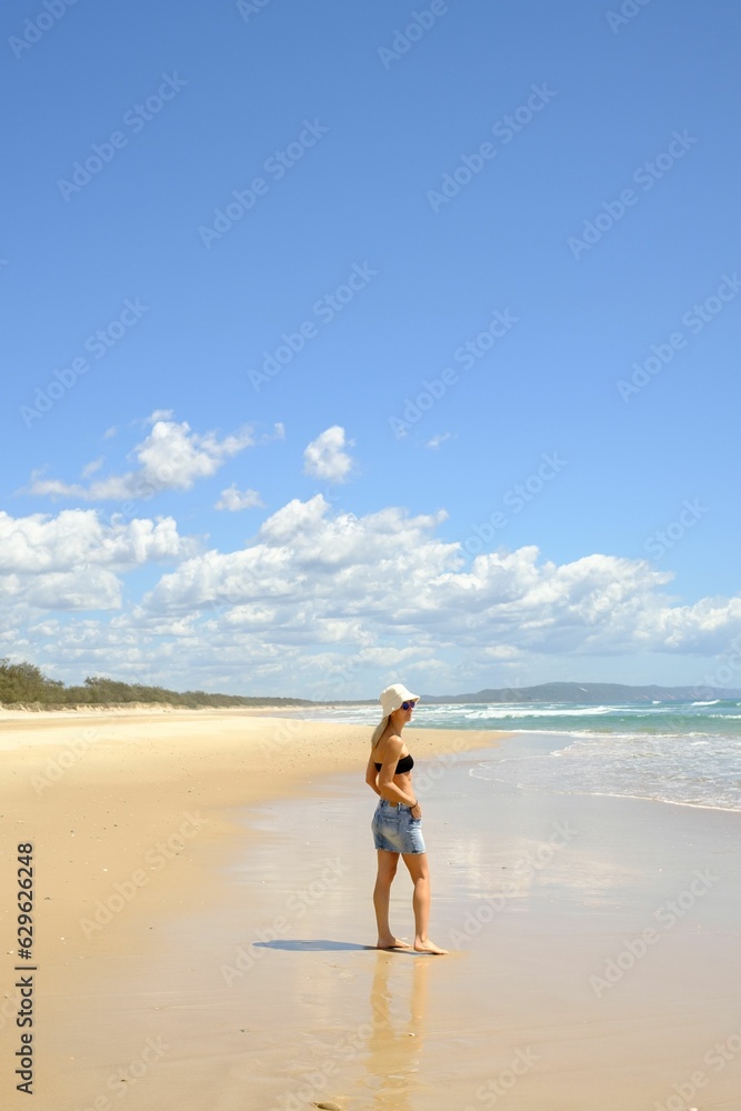Young woman in a straw hat overlooking the vast ocean horizon, Noosa North Shore Beach, Australia Young woman in a straw hat overlooking the vast ocean horizon, Noosa North Shore Beach, Australia