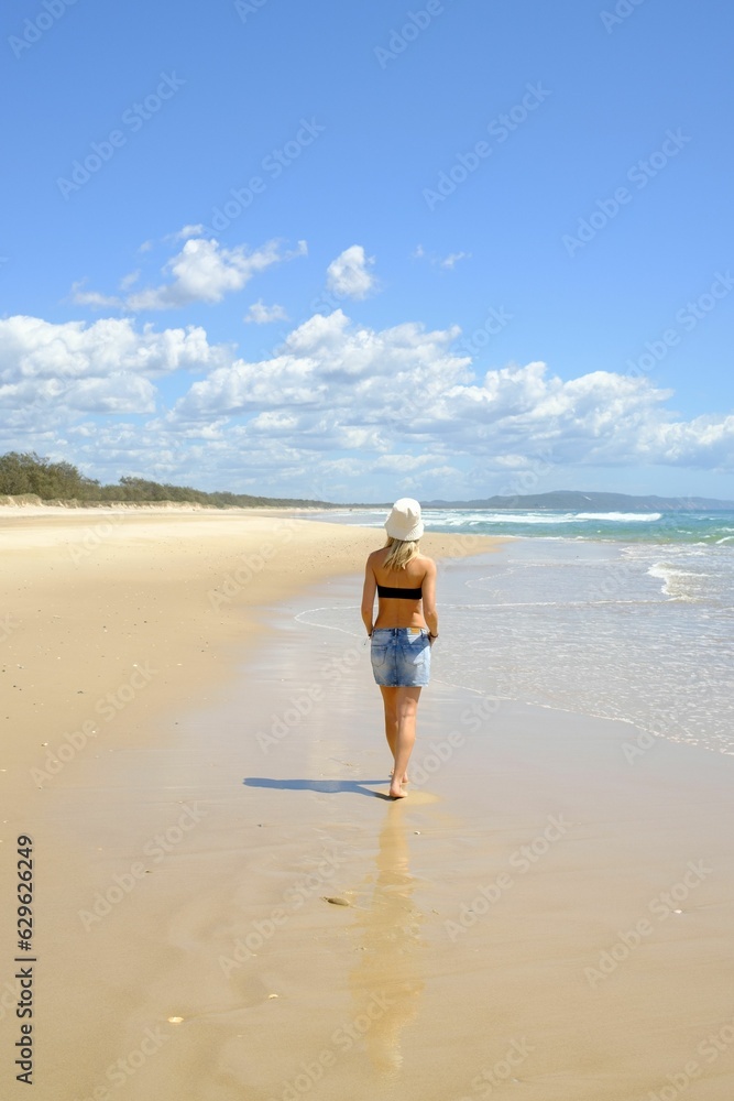 Young woman in a straw hat overlooking the vast ocean horizon, Noosa North Shore Beach, Australia Young woman in a straw hat overlooking the vast ocean horizon, Noosa North Shore Beach, Australia