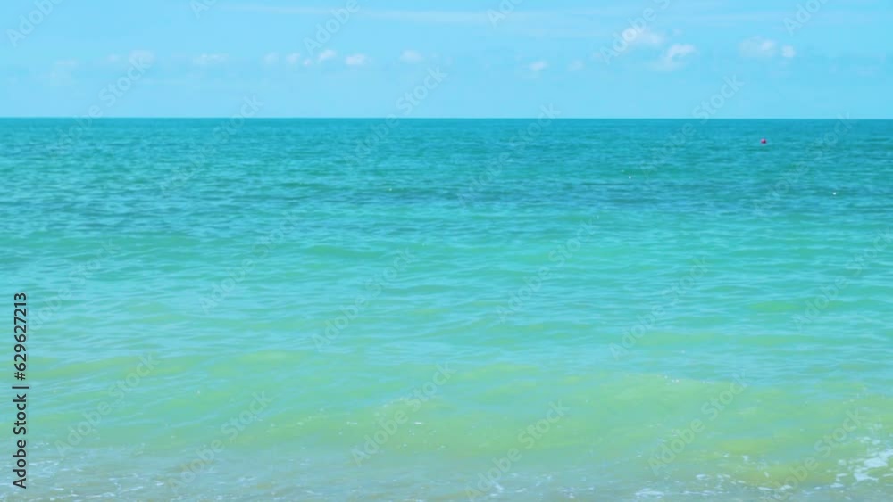 Blue Turquoise Sea Blue Sky with Light White Clouds Waves Roll on Sand, Slow Motion, Azure Water in the Ocean. Beautiful Seascape on a Sunny Summer Day. Relax, Beauty, Vacation, Horizon. Blue Turquoise Sea Blue Sky with Light White Clouds Waves Roll on Sand, Slow Motion, Azure Water in the Ocean. Beautiful Seascape on a Sunny Summer Day. Relax, Beauty, Vacation, Horizon.