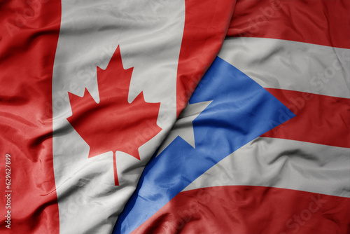 big waving realistic national colorful flag of canada and national flag of puerto rico .