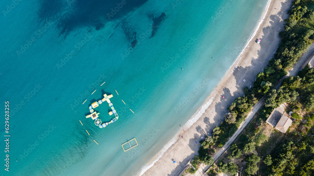 Top aerial drone view of beautiful beach with turquoise sea water and palm trees. View from above, aerial view of an emerald and transparent Mediterranean sea with a white beach