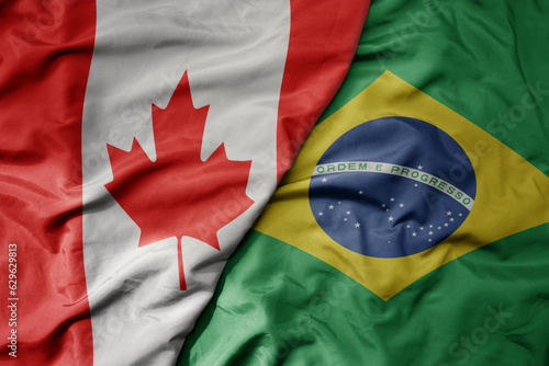 big waving realistic national colorful flag of canada and national flag of brazil . photo