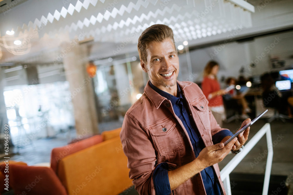 Young man using a digital tablet while working in a startup company office Young man using a digital tablet while working in a startup company office