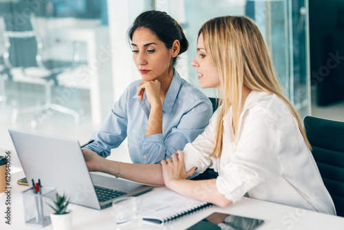 Two elegant businesswomen talking while working together in a modern startup