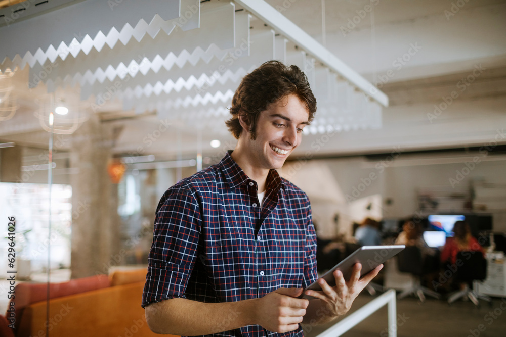 Obraz premium Young man using a digital tablet while working in a startup company office
