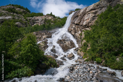 View of the Alibek waterfall formed by the fall of the Jalovchatka River from the Alibek glacier on a sunny summer day  Dombay  Karachay-Cherkessia  Russia