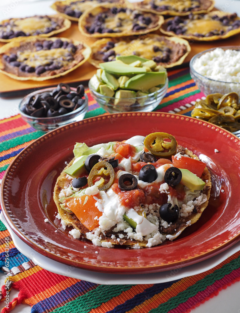 Vegetarian Tostada Topped with Toppings and Untopped Tostadas in Background Vertical Vegetarian Tostada Topped with Toppings and Untopped Tostadas in Background Vertical