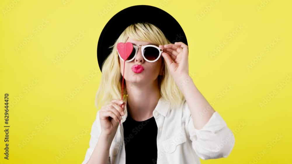 Wink, flirt and hipster woman sending air kiss and happy excited smiling. Fashionable lady blowing a kiss with confidence flirty emotion for cosmetics makeup, trendy outfit in studio yellow background Wink, flirt and hipster woman sending air kiss and happy excited smiling. Fashionable lady blowing a kiss with confidence flirty emotion for cosmetics makeup, trendy outfit in studio yellow background