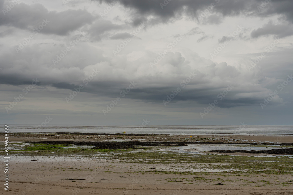 Saint-Aubin-Sur-Mer, France - 07 16 2023:  View of a cloudy rainy sky above the sea from the beach.