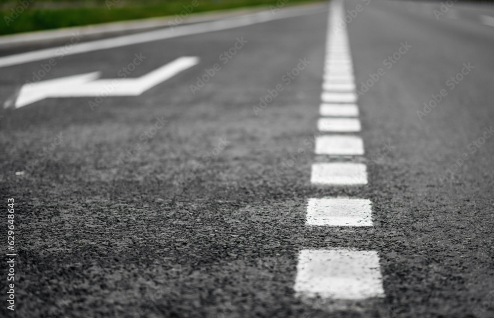 Road markings. Depth of field shot focused on asphalt close to the camera. Road with additional lane for turning right. Road markings. Depth of field shot focused on asphalt close to the camera. Road with additional lane for turning right.