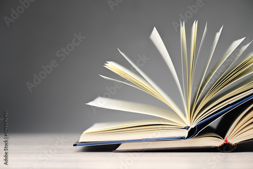 Part of two opened books stack up and spread the pages on gray wall background, with copy space