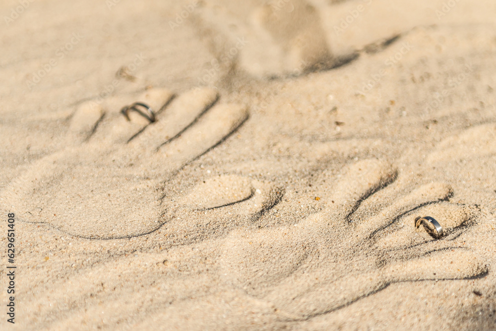 two hand prints with wedding rings on tropical sand beach, outdoor beach wedding concept two hand prints with wedding rings on tropical sand beach, outdoor beach wedding concept