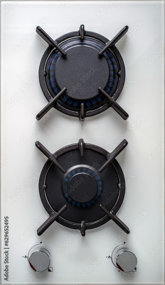 Gas is burning in two burners of a white gas stove. Gas is burning in two burners of a white gas stove.