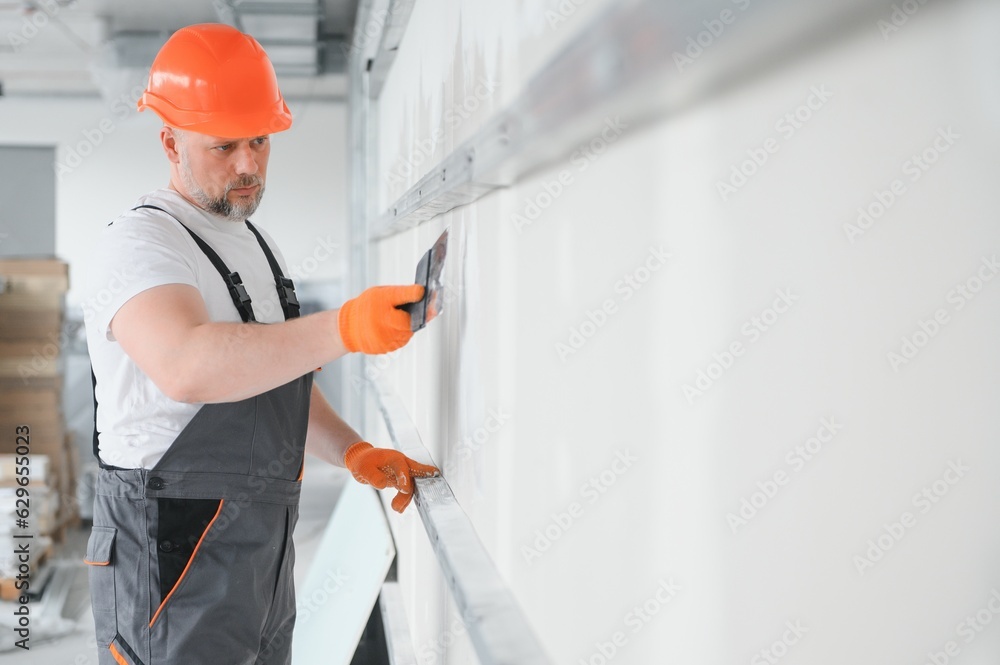 man drywall worker using trowel for plasterer putting stucco on plasterboard white wall. man drywall worker using trowel for plasterer putting stucco on plasterboard white wall.