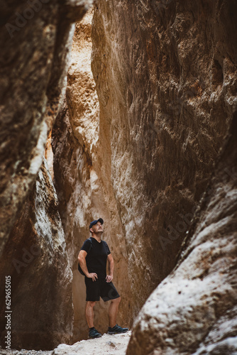 man hiker standing alone in the middle of a canyon observing the beauty of nature