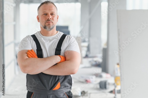 Man Builder. Architect is standing in building. Portrait of thinking builder. Builder architect in unfinished building. Architect in working uniform.