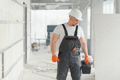 Portrait of a builder in the process of working on a construction site indoors