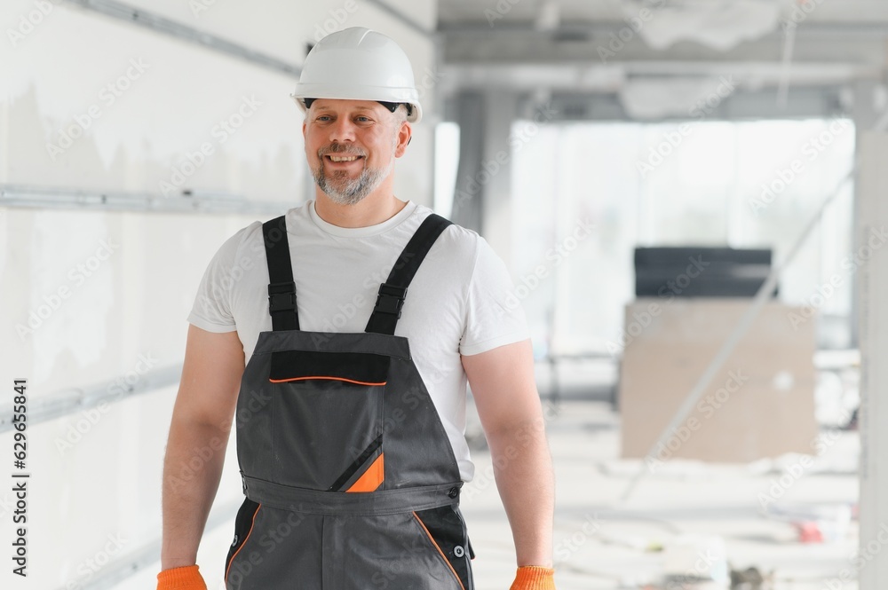 A man with a beard in a helmet and work clothes. Portrait of a worker in workwear with copy space. A man with a beard in a helmet and work clothes. Portrait of a worker in workwear with copy space.