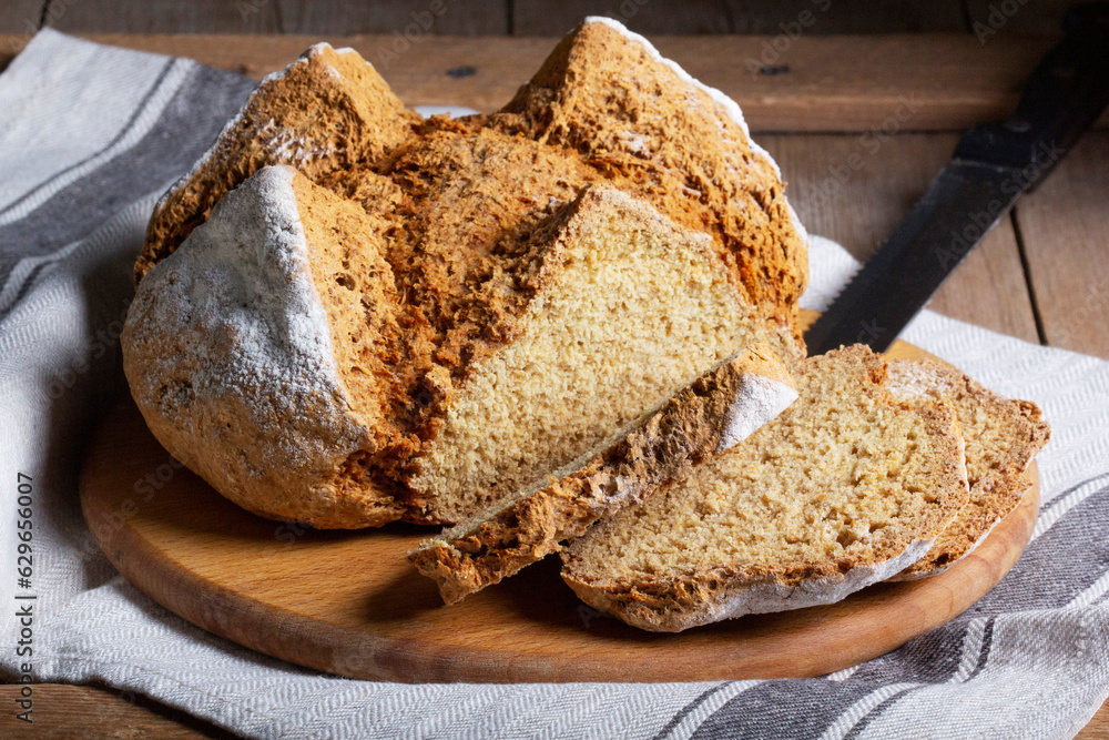 Traditional Irish soda bread made from whole grain and rye flour on a wooden table. Rustic style.