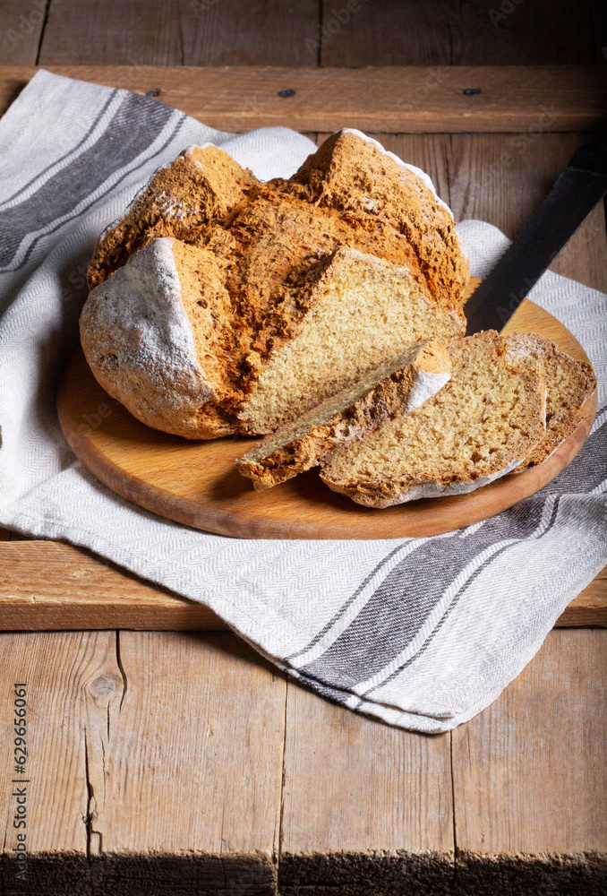Traditional Irish soda bread made from whole grain and rye flour on a wooden table. Rustic style.
