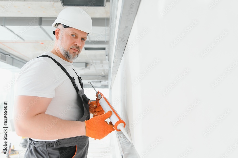 The builder fills the seams on the wall with sealed silicone The builder fills the seams on the wall with sealed silicone