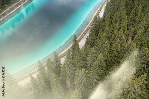 aerial view of montagnoli lake and forest surrounded by sunbeams and fog in trentino photo