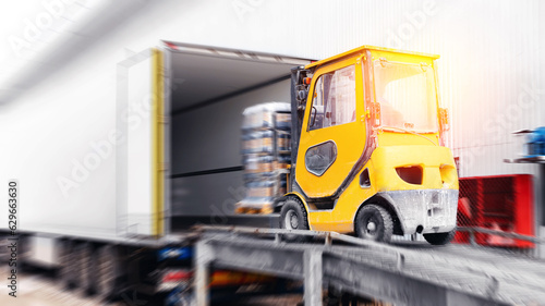 Forklift is putting cargo from warehouse to truck outdoors, sunlight motion blur effect