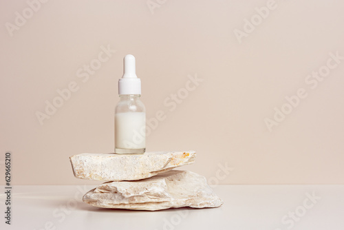 Glass dropper bottle with extract coconut or serum on natural stones, beige color background. Natural Organic Spa Cosmetic trendy concept, minimal style mock up of beauty product packaging
