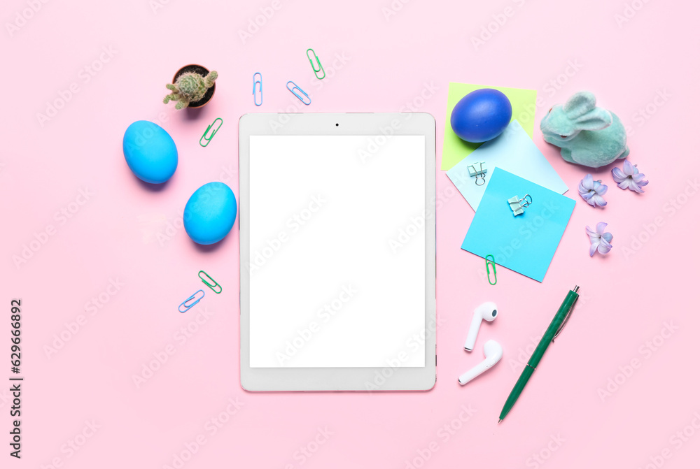 Tablet computer with office stationery, Easter eggs, rabbit and flowers on pink background Tablet computer with office stationery, Easter eggs, rabbit and flowers on pink background