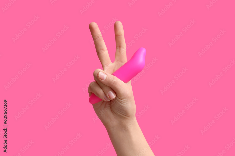 Woman with vacuum vibrator showing victory gesture on pink background Woman with vacuum vibrator showing victory gesture on pink background