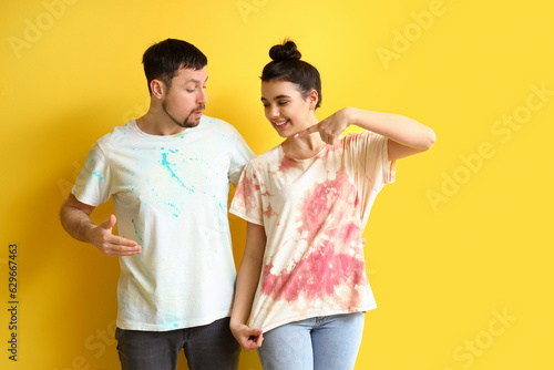Young couple in tie-dye t-shirts on yellow background
