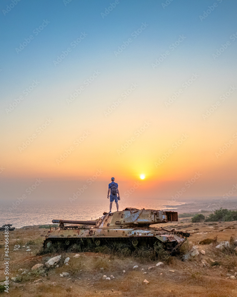 A man standing on a tank during sunset