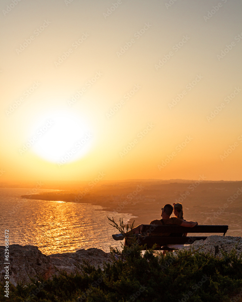 A couple enjoying sunset on a cliff.