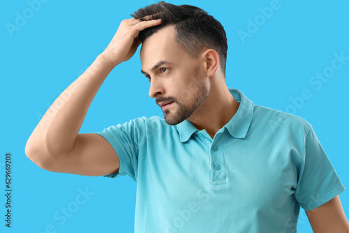 Handsome man with hair loss problem on blue background